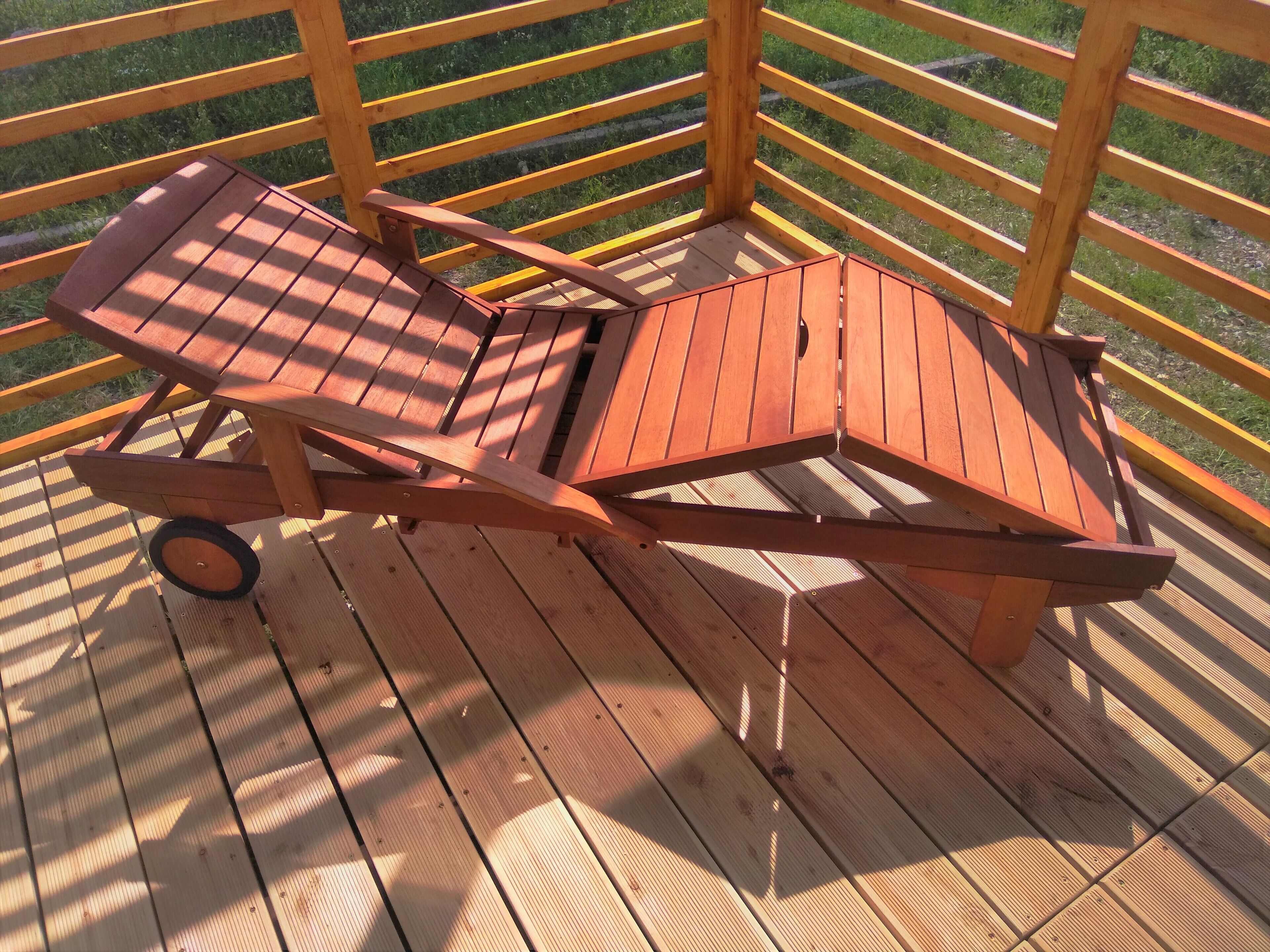 Eine Holzterrasse mit zwei Liegestühlen und einem Tisch.