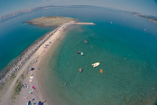 An aerial view of a coastal area with a beach, boats, and a lighthouse.
