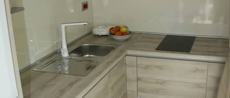 A modern kitchen with a built-in dishwasher, a sink, and a fruit bowl on the countertop.