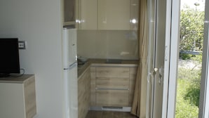 Una cocina estrecha con refrigerador, lavamanos y armarios.