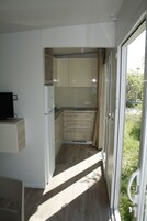 A narrow kitchen with a refrigerator, a sink, and cabinets.