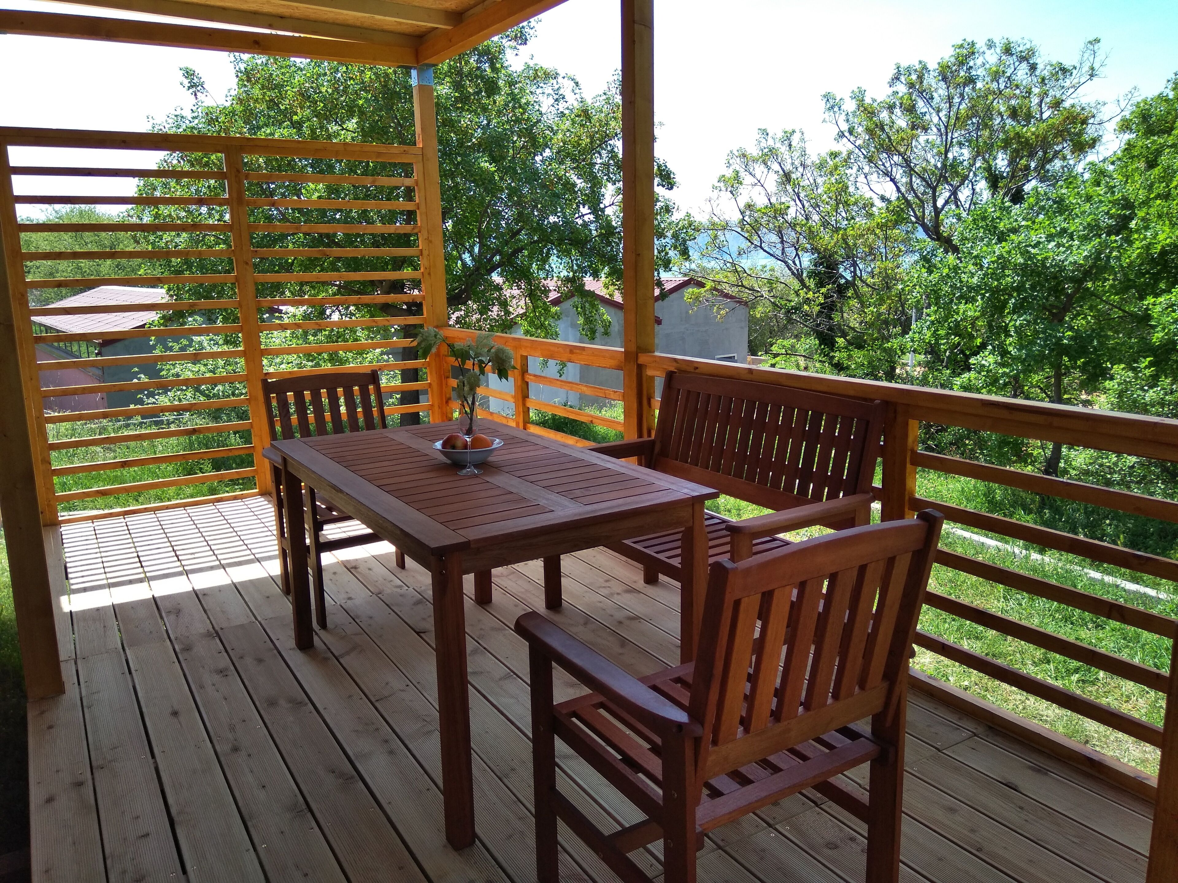 A wooden deck with a table and chairs, surrounded by a wooden railing.