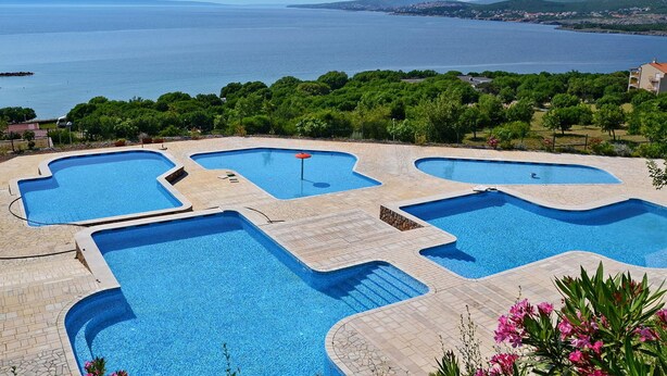 Un área de piscina con varias secciones y vistas al mar.