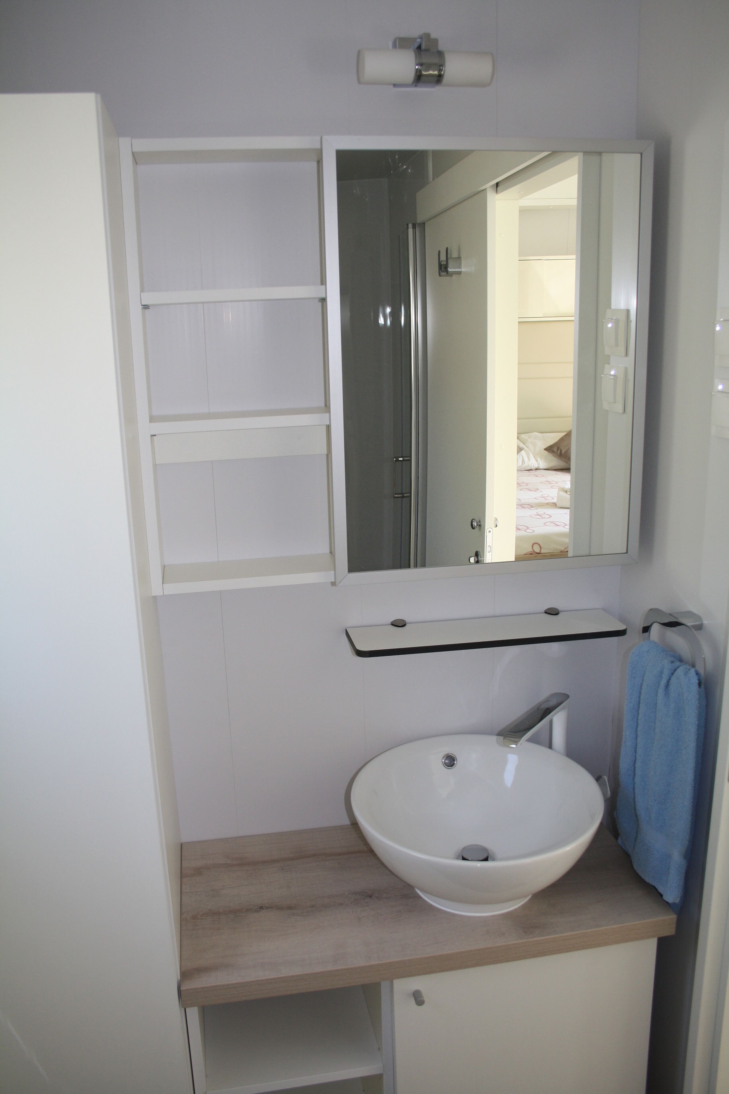 A bathroom with a white sink, a mirror above it, and a towel hanging on the wall.