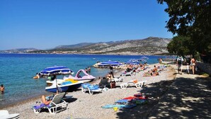 Una playa con barcos, sombrillas y gente.