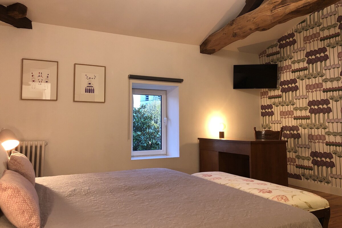 Ein Schlafzimmer mit Bett, Fenster, Kamin und Fernseher an der Wand.