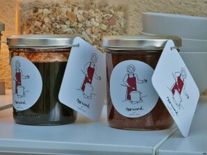 Drei Gläser Marmelade mit Etiketten, die Illustrationen einer Köchin zeigen.