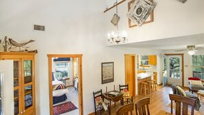 A spacious living area with a dining table, chairs, a chandelier, and a view of the outdoors. - Creekside Country Guesthouse | 2 Bedroom plus loft | Beautiful Country Setting (Fredericksburg)