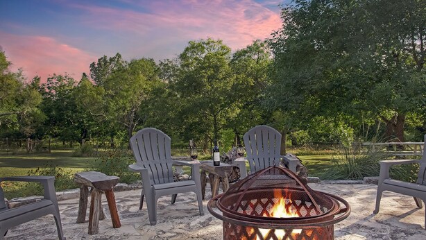 An outdoor seating area with Adirondack chairs and a fire pit. - Creekside Country Guesthouse | 2 Bedroom plus loft | Beautiful Country Setting (Fredericksburg)