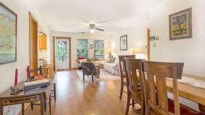 A spacious living room with a dining area, wooden furniture, and a ceiling fan. - Creekside Country Guesthouse | 2 Bedroom plus loft | Beautiful Country Setting (Fredericksburg)