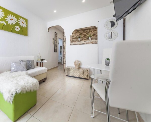 A modern living room with a green sofa, white armchair, and a small table with decorative items. - A40 - Castle Arch Apartment (Lagos)