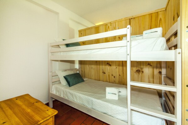 A bunk bed with a wooden headboard, a small wooden table, and a white wall.