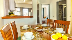 Un comedor con una mesa preparada para cuatro personas, incluyendo platos, vasos y un bol de limones.