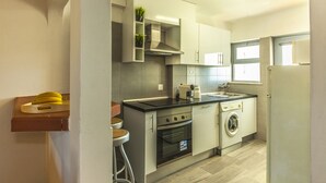 Cocina compacta con estufa, horno, fregadero y lavadora integrada.
