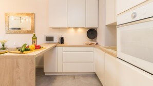 Una cocina moderna con armarios blancos, un microondas, un ventilador y una encimera de madera con verduras frescas.