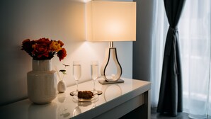A table with a vase of flowers, two glasses of champagne, and a plate with a dessert. - B&B Stramondo (Catania)