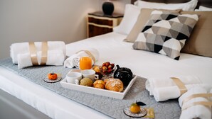 A neatly made bed with a tray of breakfast items, including croissants and fruit, and a bottle of orange juice. - B&B Stramondo (Catania)