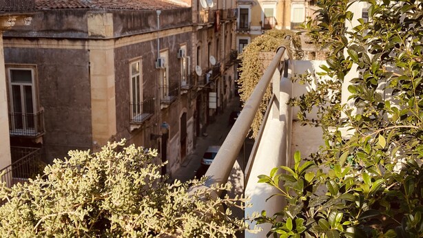 A narrow street flanked by buildings with balconies and satellite dishes, suggesting a residential area. - B&B Stramondo (Catania)