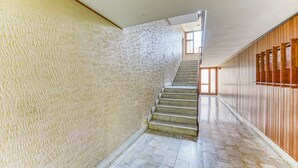 A staircase with a textured wall on one side and wooden paneling on the other, leading to an upper floor. - Casa Arno 500m from beach (Massa)