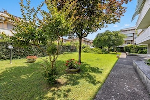 A well-maintained courtyard with a pathway, trees, and flower beds. - Casa Arno 500m from beach (Massa)