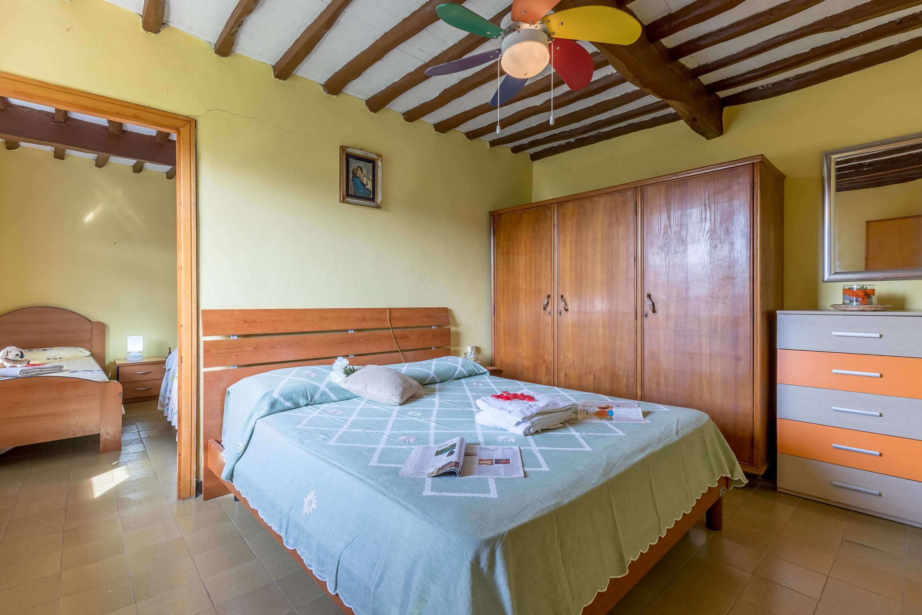 Ein Schlafzimmer mit einem Bett, einem Holzschrank und einem Deckenventilator.