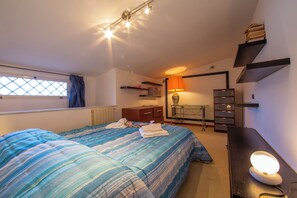 Cozy retreat with a large bed, bedside table, dresser, and desk, offering a comfortable space to unwind.