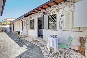 Experience the serene charm of this traditional building, featuring a courtyard with a cozy outdoor seating area and a picket fence.