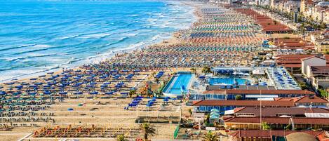 A beach resort with multiple swimming pools, beach umbrellas, and a long stretch of beach.