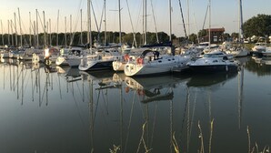 Un port de plaisance où sont amarrés de nombreux voiliers, l’eau est calme et le ciel est dégagé.