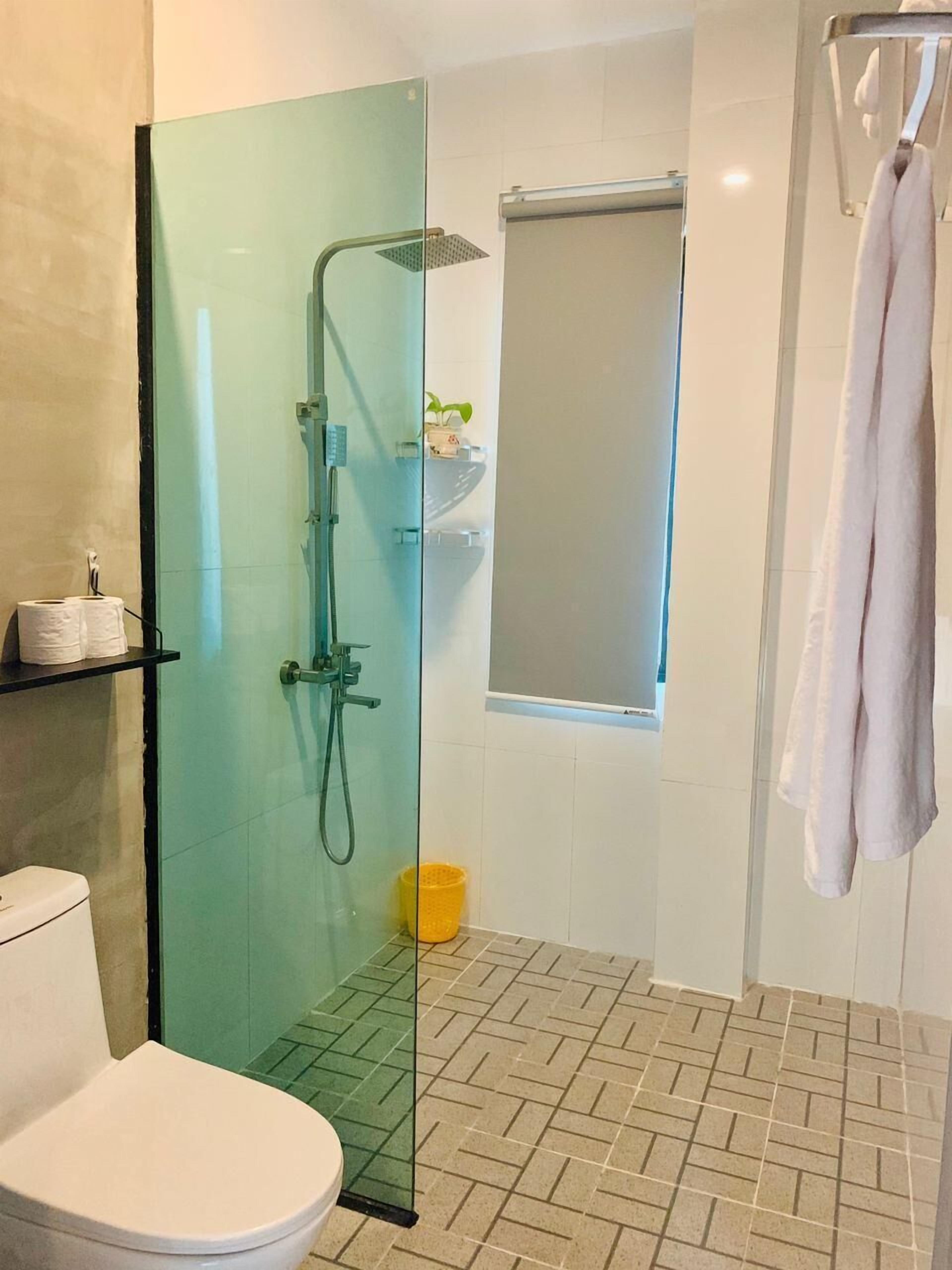 A modern bathroom with a glass-enclosed shower, a toilet, a sink with a shelf, and a towel rack.