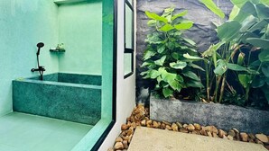 A modern bathroom with a shower, a small sink, and a green wall. - Raing Phnom Bungalow (Kampot)