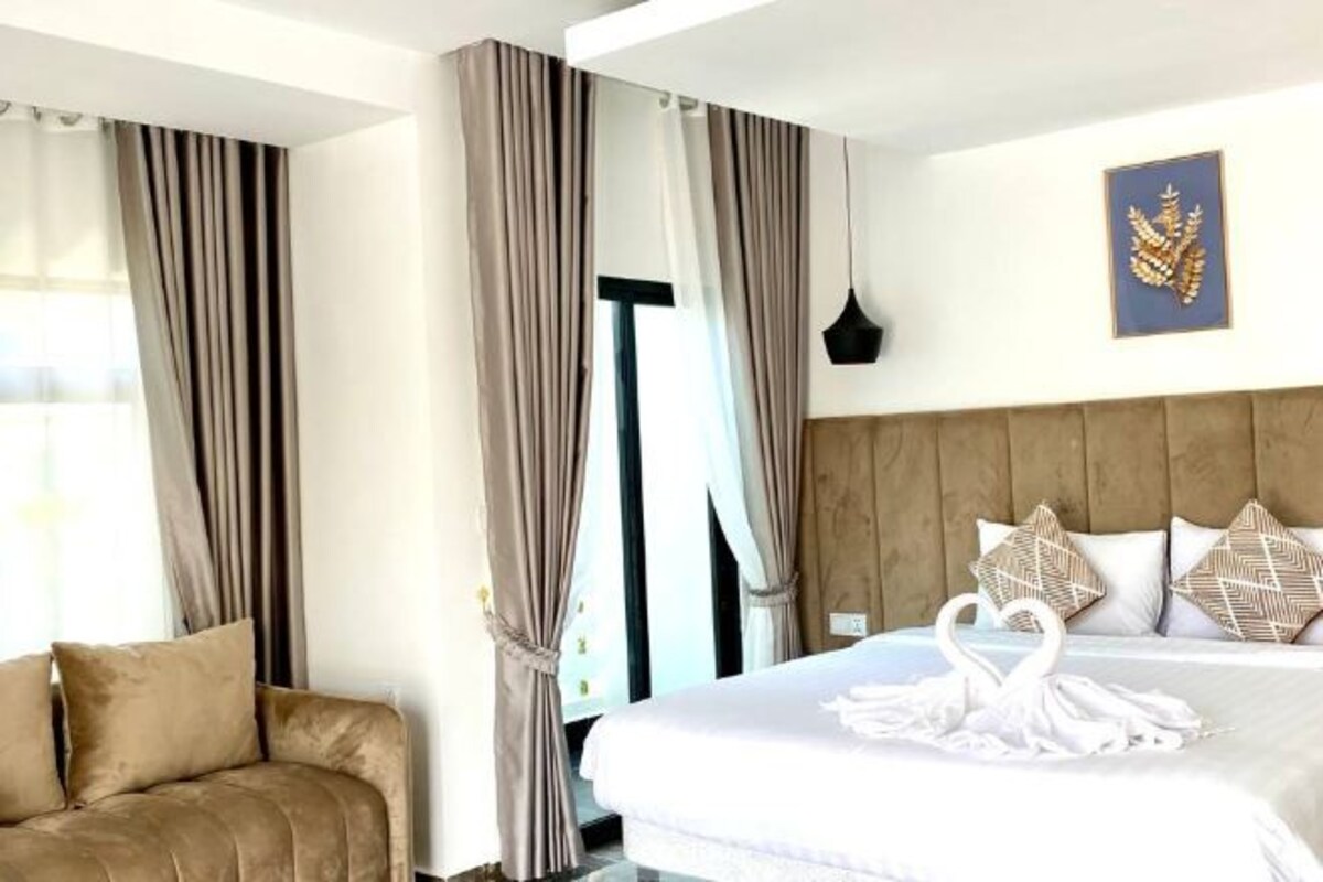 Ein Hotelzimmer mit einem Bett, einer Couch und einem Vorhangfenster.