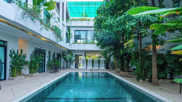 An indoor swimming pool with clear water, surrounded by lush greenery and modern architecture. - Raing Phnom Bungalow (Kampot)