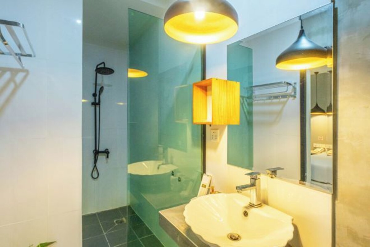 Ein modernes Badezimmer mit einer Duschkabine aus Glas, einem weißen Waschbecken und einem Spiegel mit Holzablage.