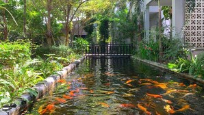 A koi pond with a wooden walkway and lush greenery. - Raing Phnom Bungalow (Kampot)