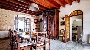 Un coin repas avec une table et des chaises en bois, un grand meuble et un mur en pierre.