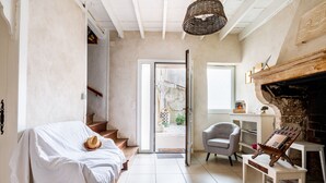 Une chambre à coucher avec un lit, une chaise, une cheminée et une vue sur l’extérieur, visible à travers une porte.