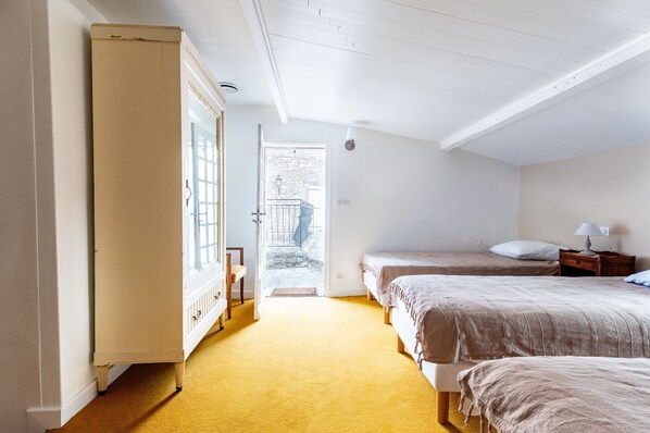 A room with two beds, a wooden wardrobe, and a door leading outside.