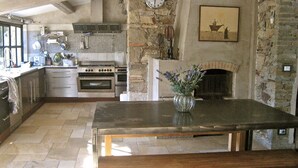 A rustic kitchen with stone walls, a wooden ceiling, and a fireplace. - Charming residence in Grimaud (Grimaud)