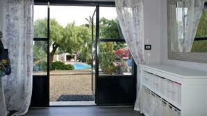 A room with a sliding glass door leading to an outdoor area with a pool and greenery. There is a white dresser with drawers and a mirror on the wall. - Charming residence in Grimaud (Grimaud)