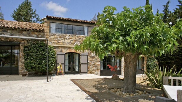 A stone building with large windows and a wooden deck. - Charming residence in Grimaud (Grimaud)