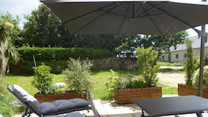 An outdoor patio with a table and two lounge chairs under a large umbrella.