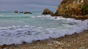 A rocky shoreline with waves crashing onto the pebbles.