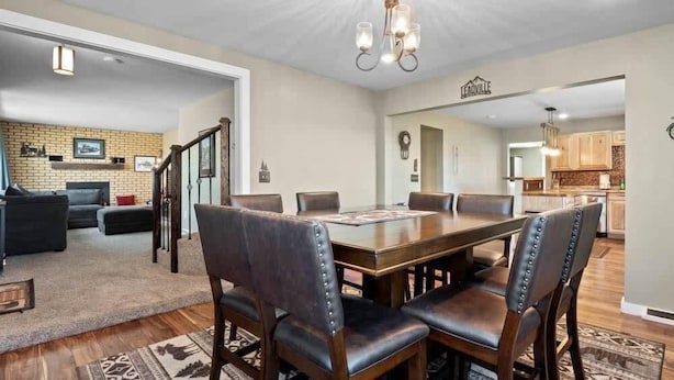 Un comedor con mesa de madera y sillas de cuero, una cocina con armarios de madera y una sala de estar con chimenea.