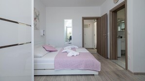 A bedroom with a bed, a mirror, a door leading to a bathroom, and a view of the outside. - 2 bedroom gorgeous apartment in Podaca (Podaca)