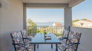 A balcony with a table and chairs, overlooking a scenic view of a lake and mountains. - 2 bedroom gorgeous apartment in Podaca (Podaca)