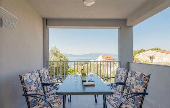A balcony with a table and chairs, overlooking a scenic view of a lake and mountains. - 2 bedroom gorgeous apartment in Podaca (Podaca)