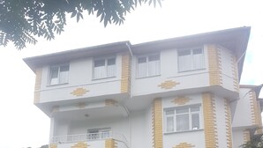 Un edificio de varios pisos con fachada blanca y detalles dorados, que cuenta con un balcón y una tienda con letreros.