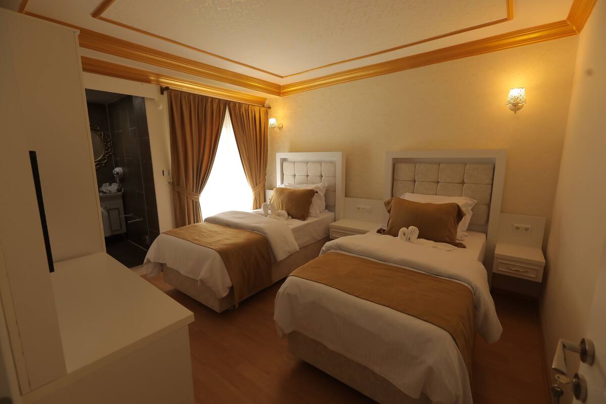 A hotel room with two beds, a bathroom, and a small seating area.