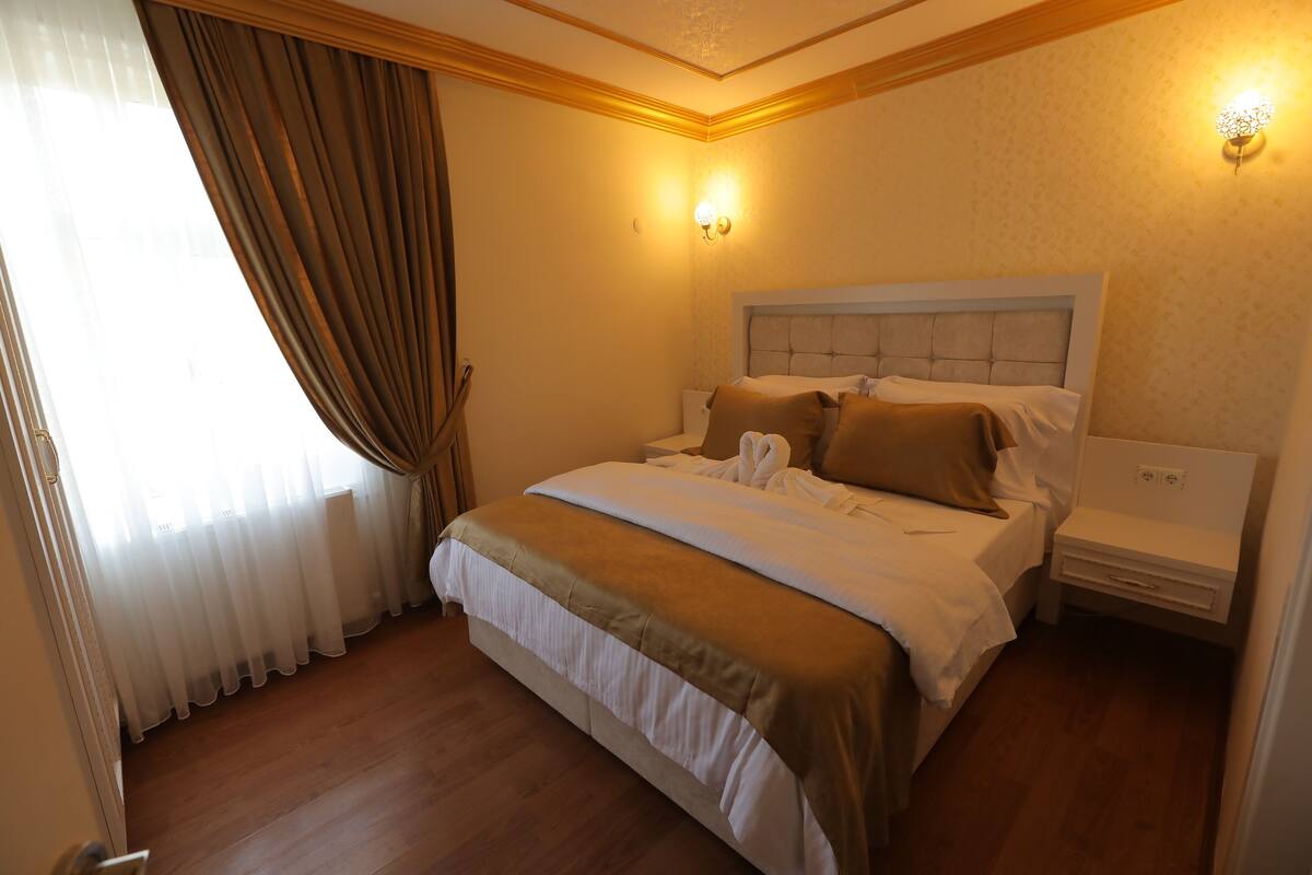 A hotel room with a large bed, a bedside table, and a nightstand.
